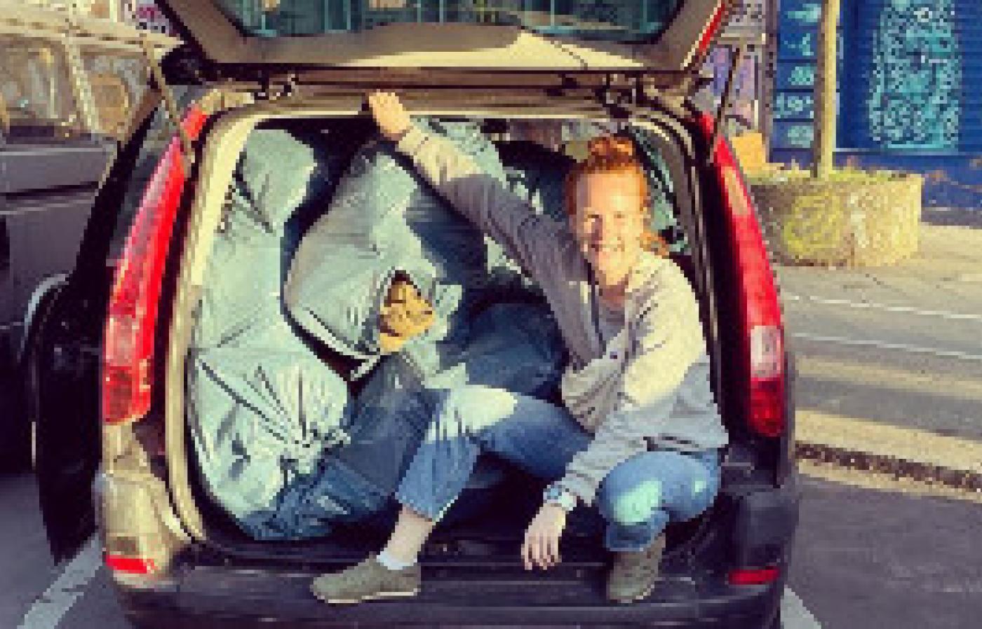 Hannah Zurjanova crouches on the tailgate of her minivan full of supplies for Ukrainian soldiers