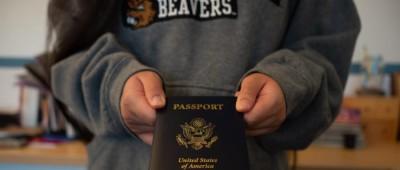student in beaver sweatshirt holding passport